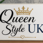 A decorative white plaque with elegant black calligraphy spelling 'Queen Style UK' framed in gold, featuring a golden crown above the word 'Queen', a blue 'UK', and a delicate gold flourish below. The plaque rests on a wooden surface with soft indoor lighting and a patterned wallpaper backdrop, creating an upscale royal aesthetic.