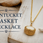 Nantucket basket necklace gold pendant featuring woven basket design on coastal beach background, elegant Nantucket basket necklace jewelry close-up.